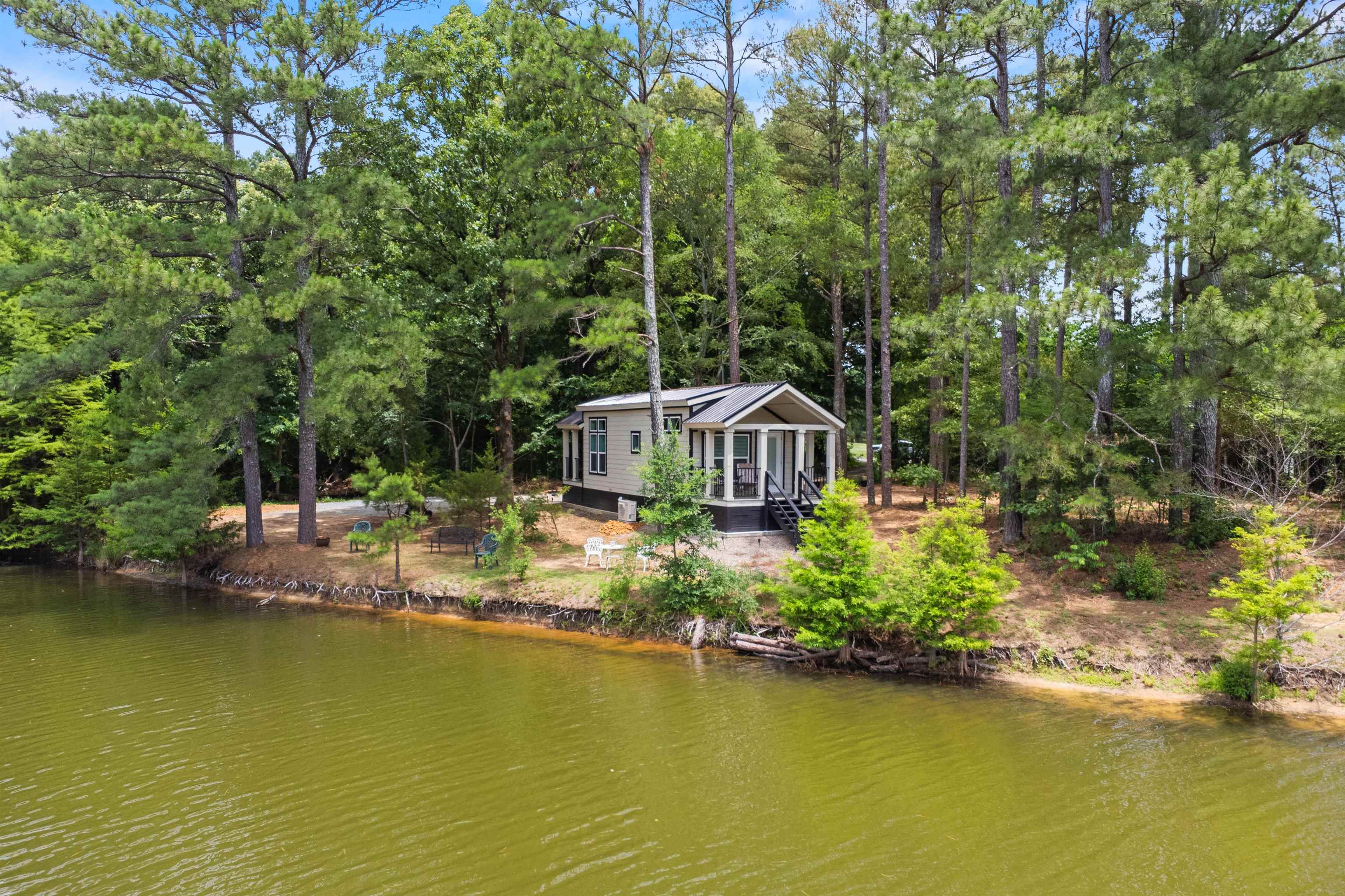 330 Whitley Road Oakland, TN 38060 - Photo 1 of 19 Waterfront property featuring a sunroom with expansive windows, elevated porch with dark railings, and a surrounding natural landscape of mature trees