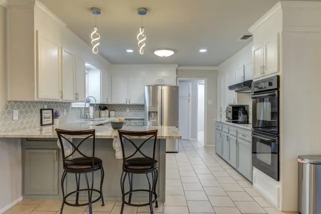 a kitchen with stainless steel appliances kitchen island granite countertop a refrigerator a stove a sink dishwasher and a dining table with wooden floor
