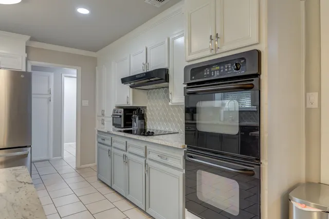 a kitchen with white cabinets and appliances