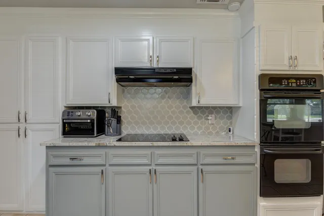 a kitchen with a stove and white cabinets