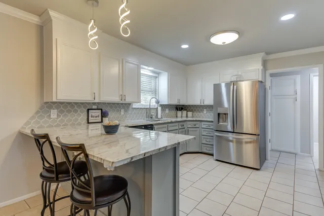 a kitchen with a refrigerator a stove a sink and chairs