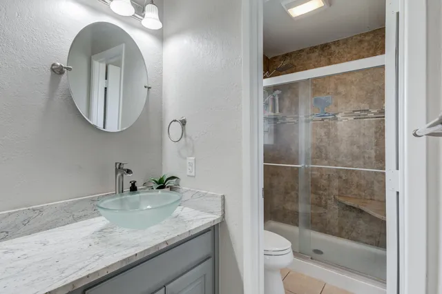 a bathroom with a granite countertop sink a toilet and a mirror