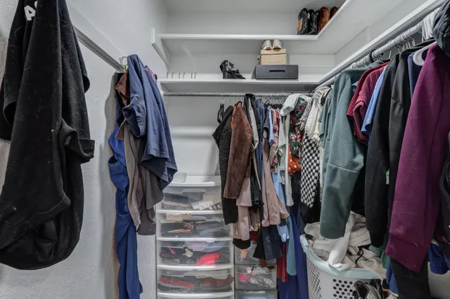 a view of walk in closet with clothes and shoes