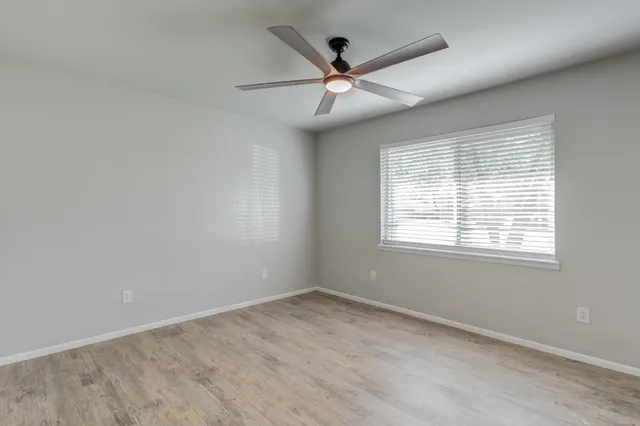 an empty room with a window and a fan