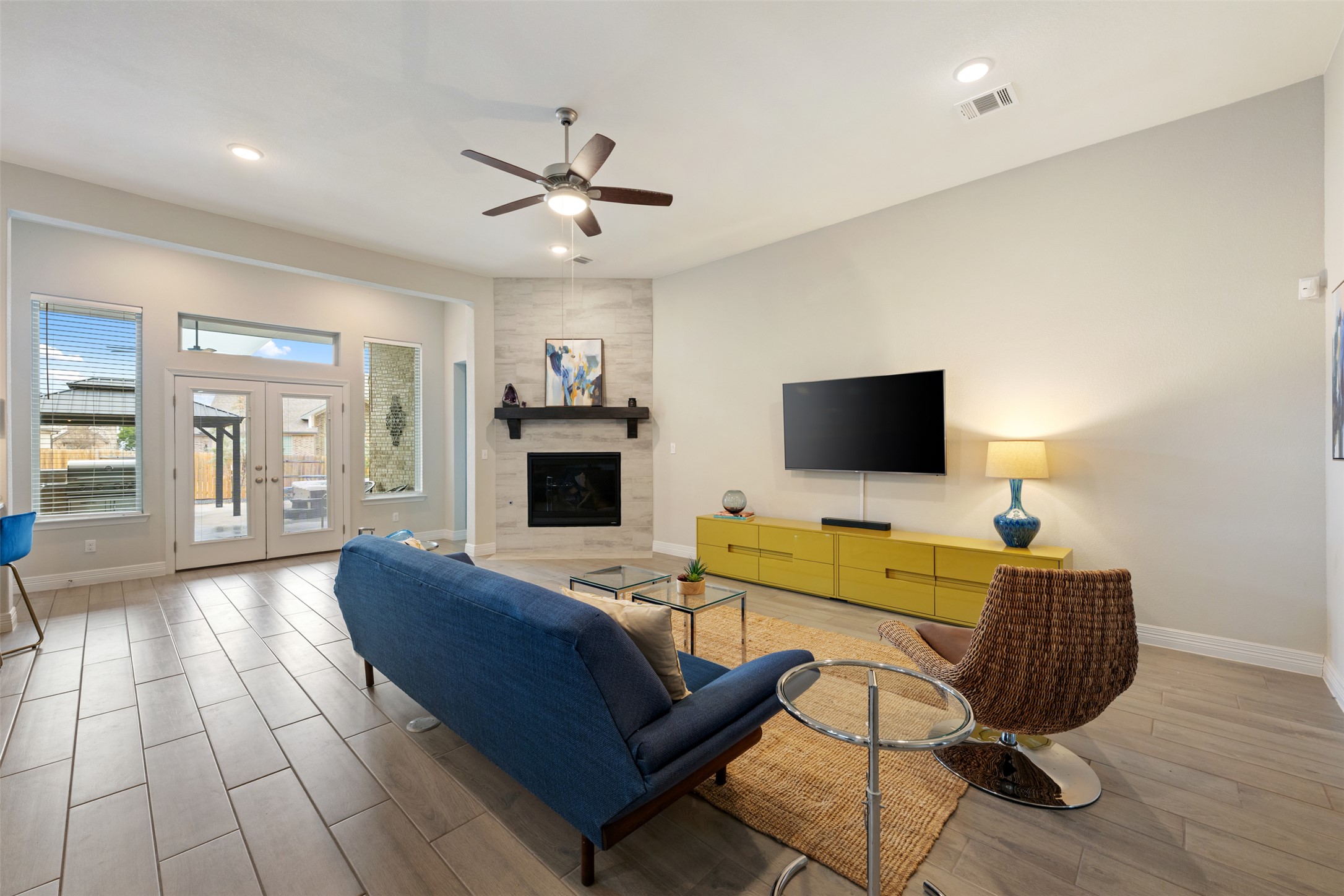 2501 Costera Street Leander, TX 78641 - Photo 7 of 40 Living room with wood floors, recessed lighting, ceiling fan. fireplace with gas logs and French doors leading out to the extended patio.