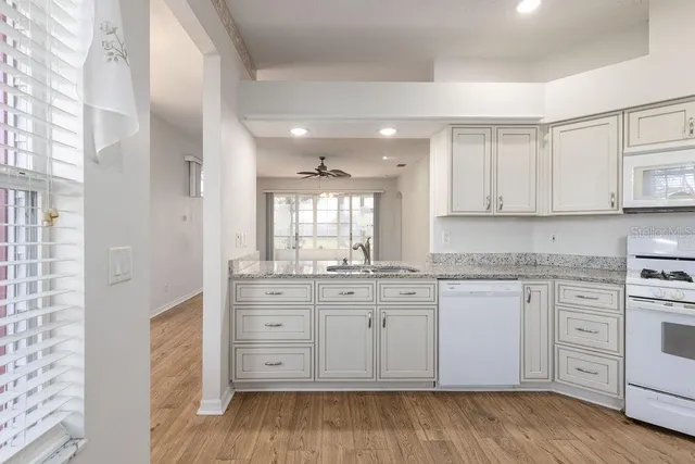 a kitchen with granite countertop white cabinets and white appliances