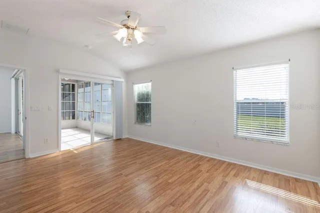 a view of an empty room with a window and wooden floor