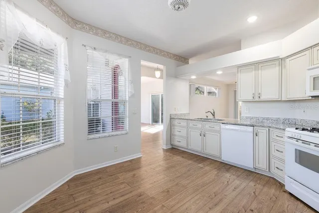 a large kitchen with a wooden floor and white cabinets