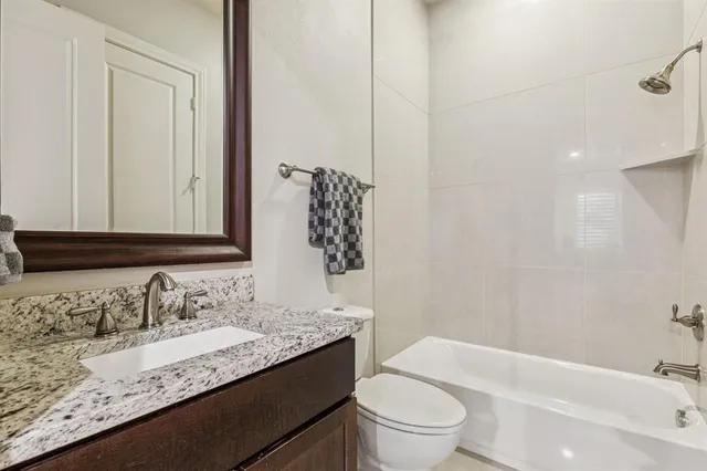a bathroom with a granite countertop sink a toilet and bathtub