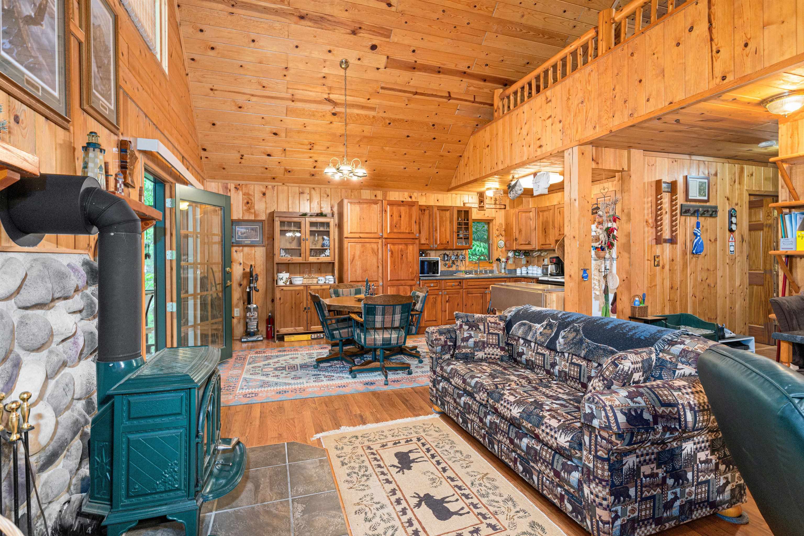 1207 Christianson Lake Road Two Harbors, MN 55616 - Photo 13 of 36 Living area with wooden walls, a wood stove, light wood-style flooring, wood ceiling, and high vaulted ceiling