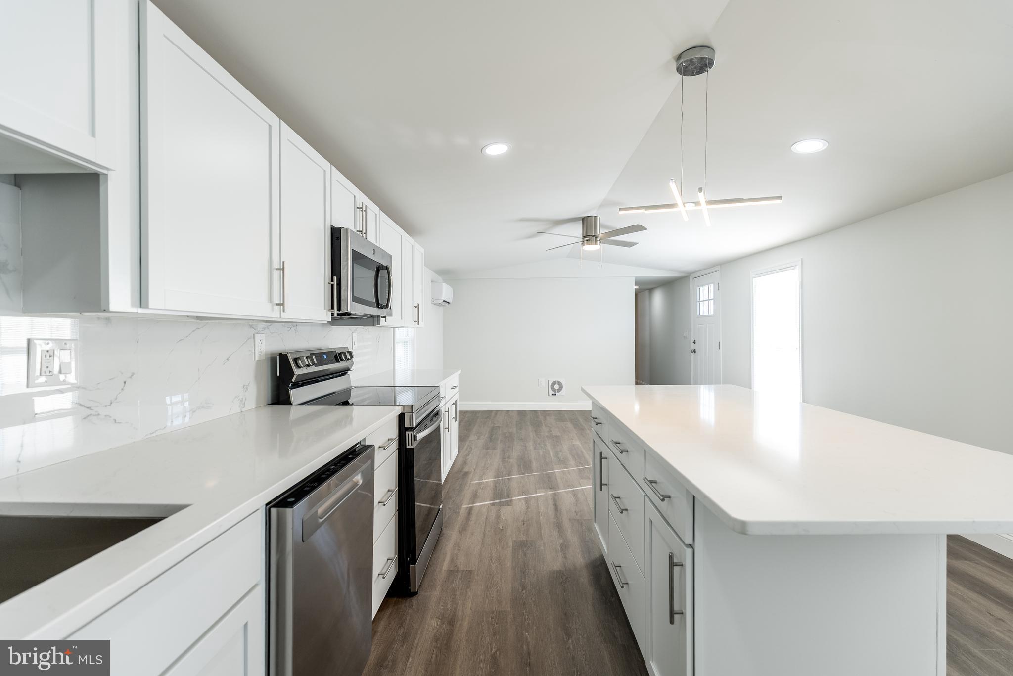 115 5th Street, Unit 40 Delaware City, DE 19706 - Photo 2 of 12 a large kitchen with stainless steel appliances lots of counter space and wooden floor