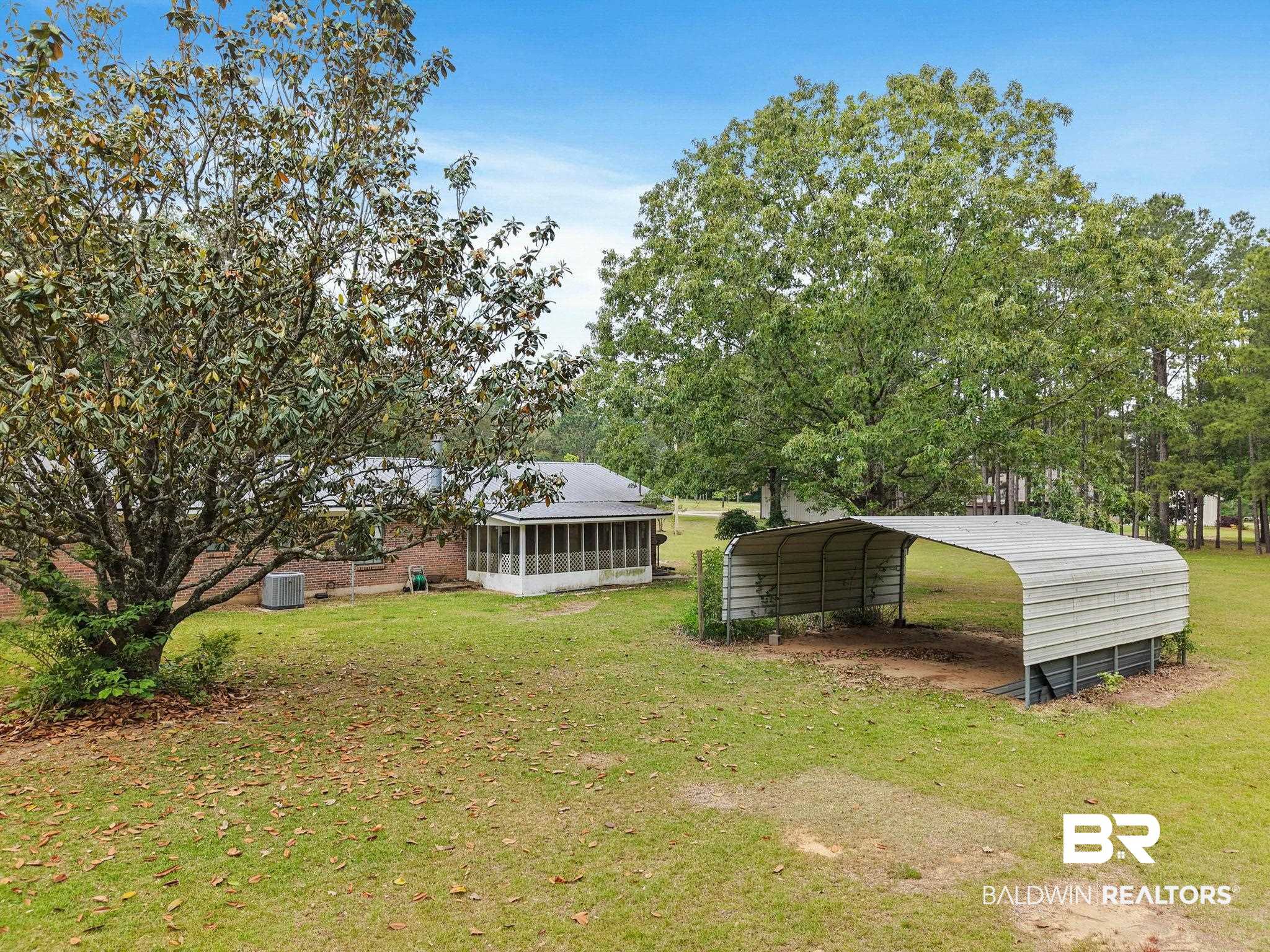 13653 Roberts Road Loxley, AL 36551 - Photo 29 of 33 Expansive rear yard featuring mature trees, a detached carport, a screened porch, and a brick exterior dwelling