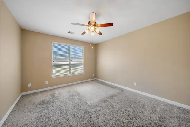 an empty room with windows and fan