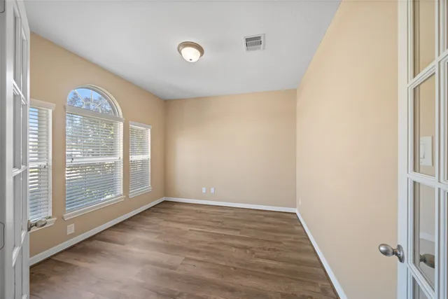 a view of empty room with wooden floor and fan