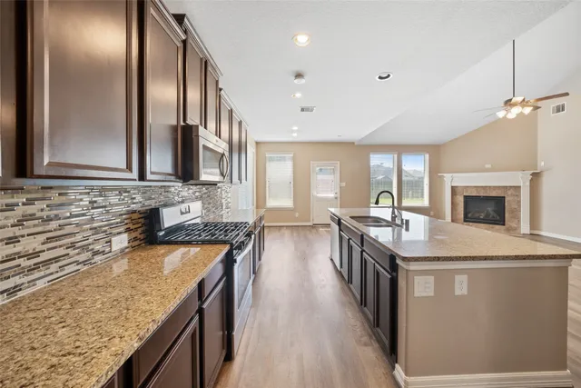 a kitchen with stainless steel appliances granite countertop a sink a stove and a wooden floors