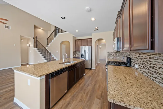 a large kitchen with kitchen island a island wooden cabinets and stainless steel appliances