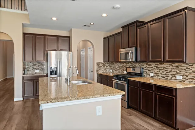a kitchen with stainless steel appliances granite countertop a sink stove and refrigerator