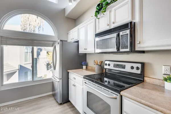 a kitchen with stainless steel appliances granite countertop a sink window and cabinets