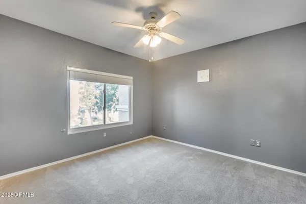 an empty room with windows and chandelier fan