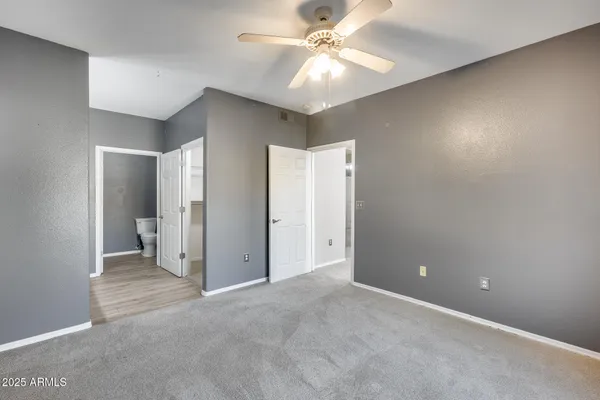 an empty room with closet and a ceiling fan