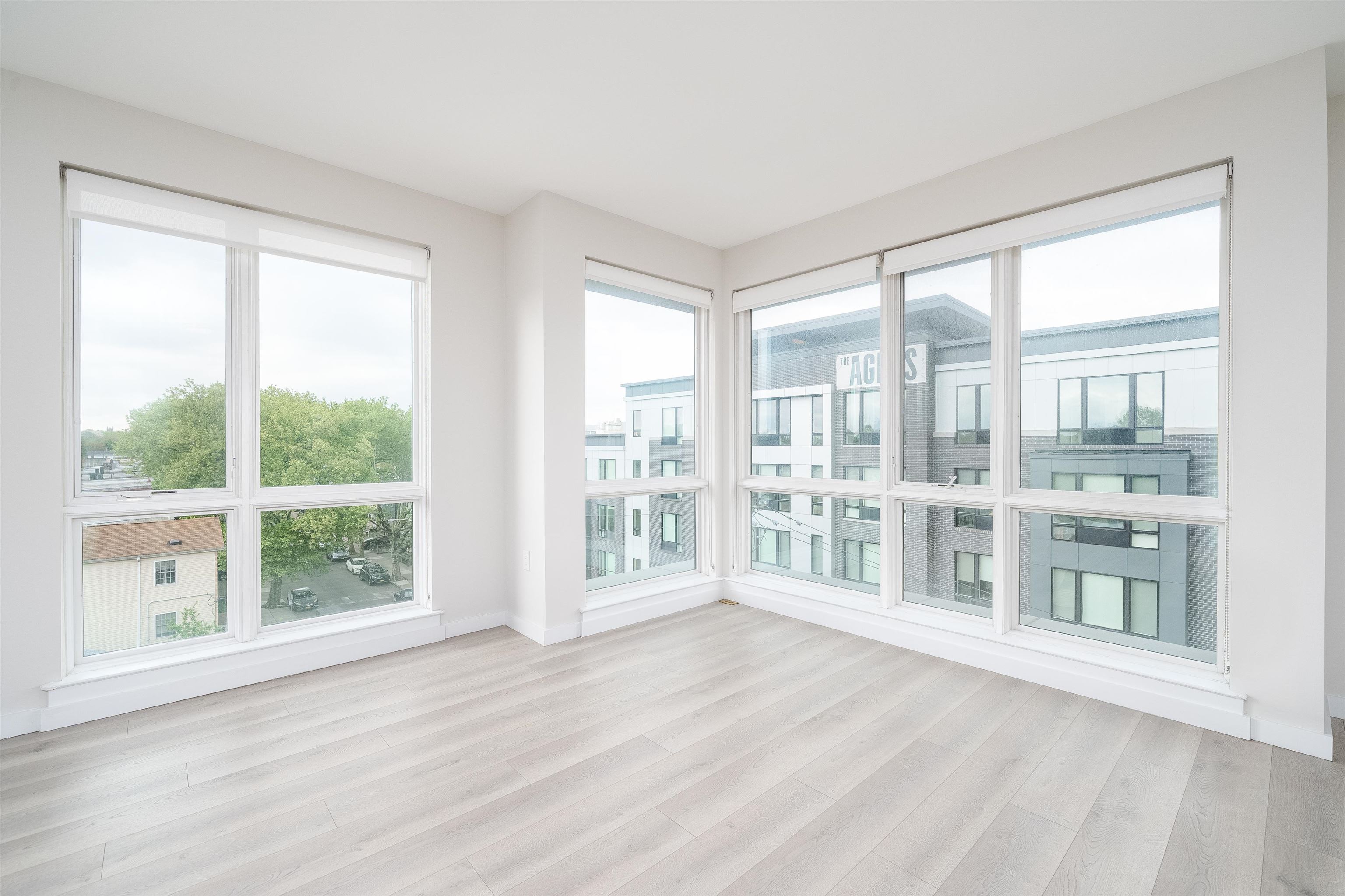 16 Bennett Street, Unit 211 Jersey City, NJ 07304 - Photo 6 of 24 a view of an empty room with wooden floor and windows