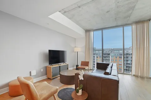 a living room with furniture a flat screen tv and a floor to ceiling window