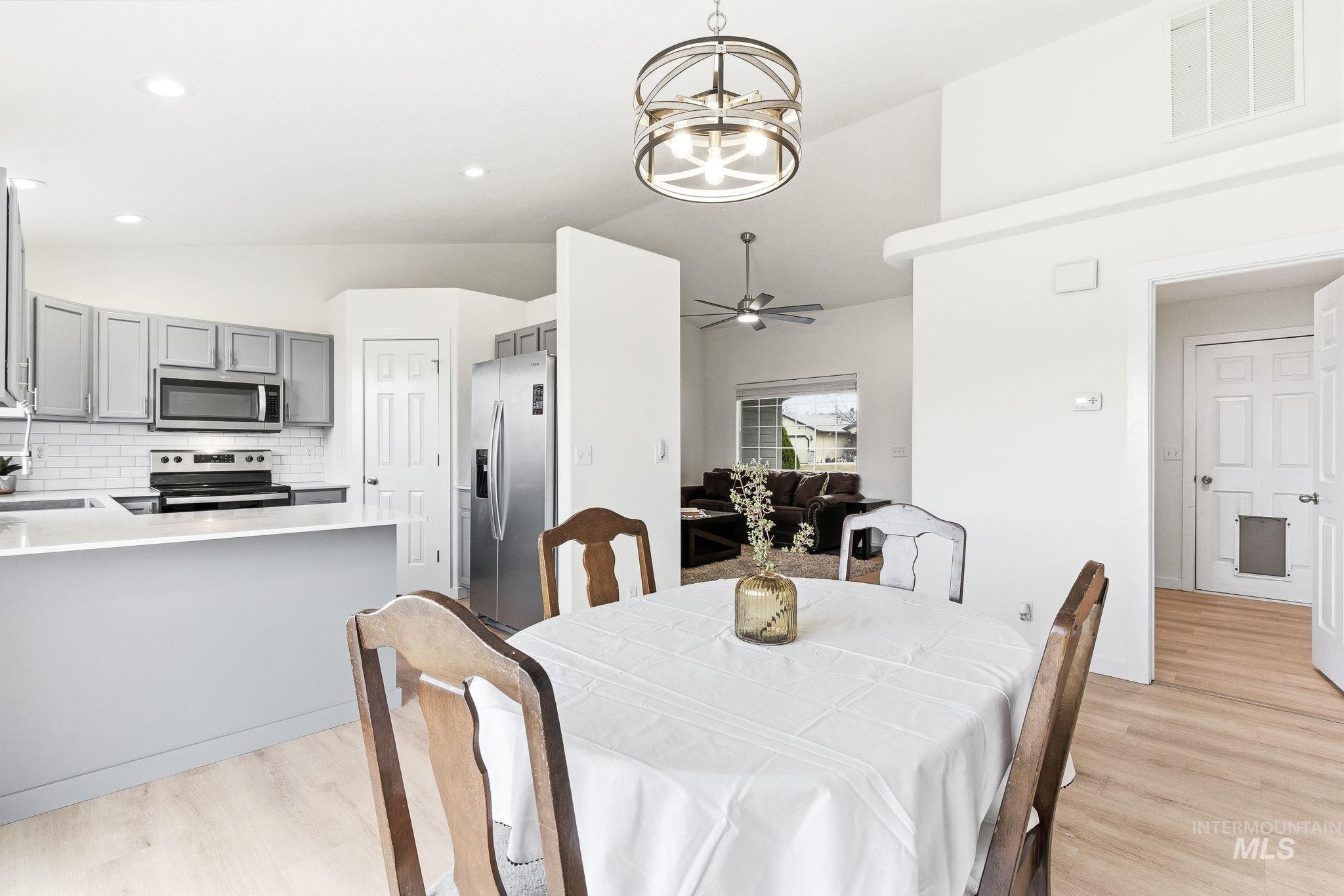 696 West Rams Hill Street Kuna, ID 83634 - Photo 12 of 46 Dining room featuring lofted ceiling, suspended lighting, light wood finished floors, and a ceiling fan