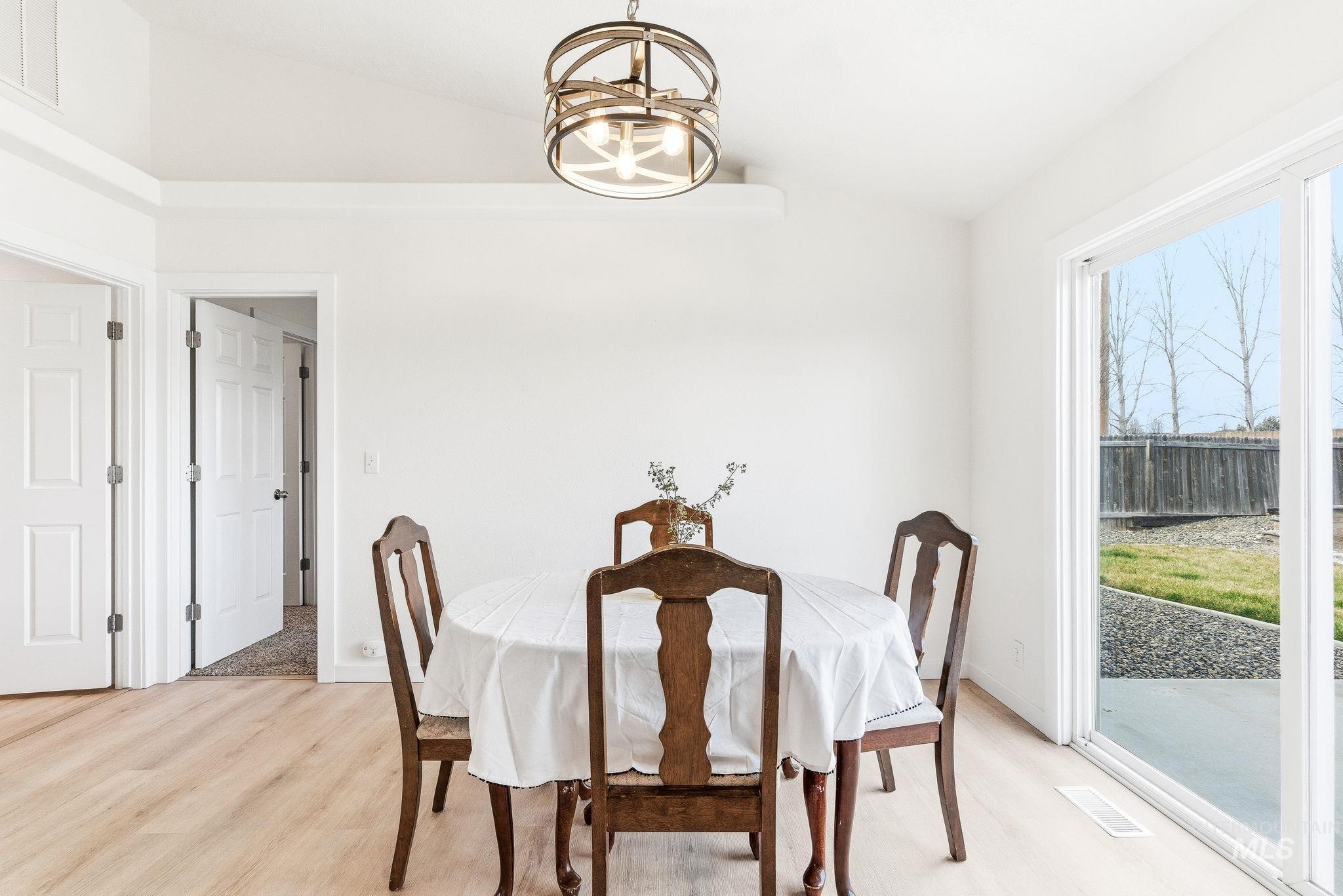 696 West Rams Hill Street Kuna, ID 83634 - Photo 13 of 46 Dining room featuring lofted ceiling, light wood finished floors, and hanging lights