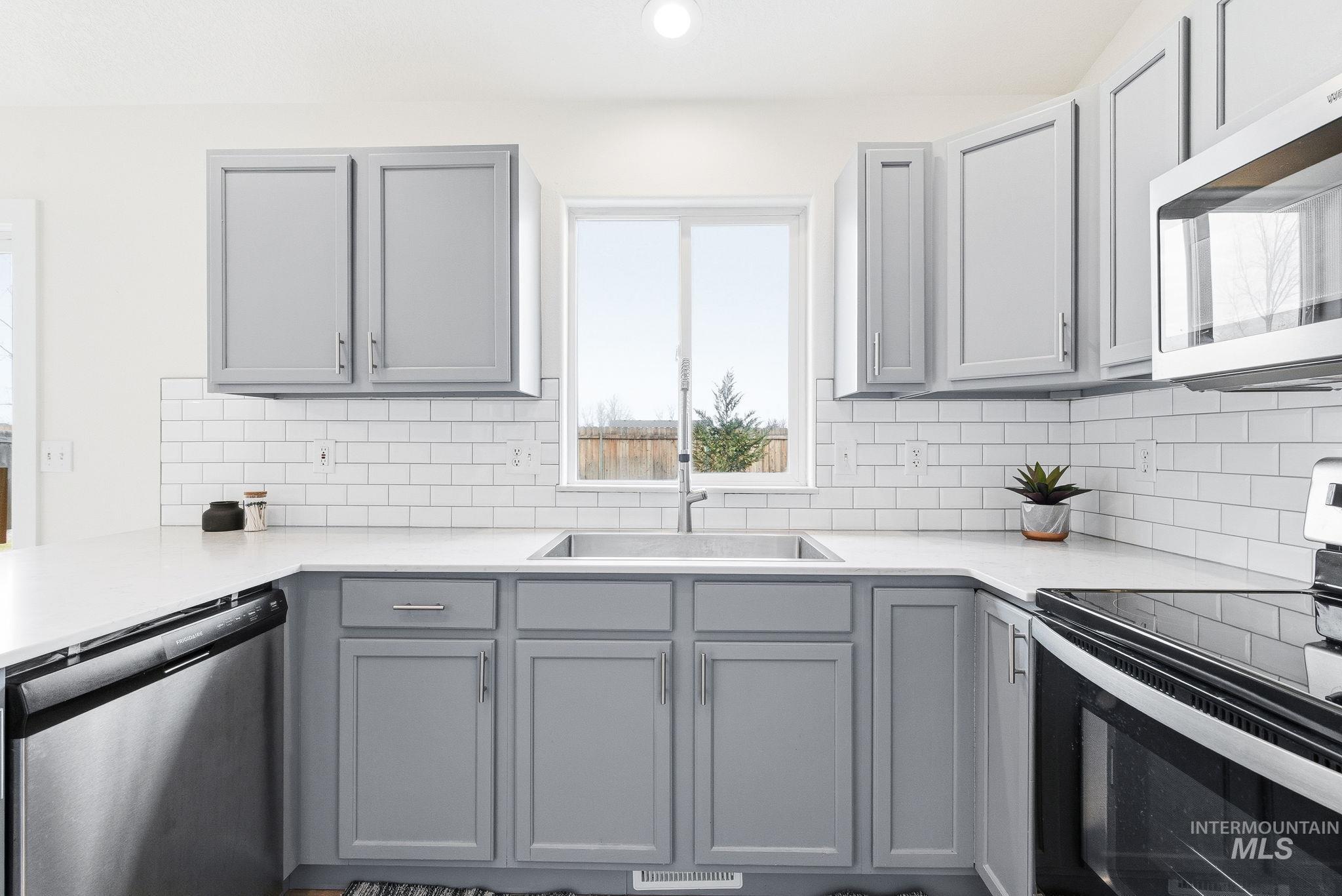 696 West Rams Hill Street Kuna, ID 83634 - Photo 17 of 46 Kitchen featuring gray cabinetry, stainless steel appliances, decorative backsplash, recessed lighting, and light stone counters