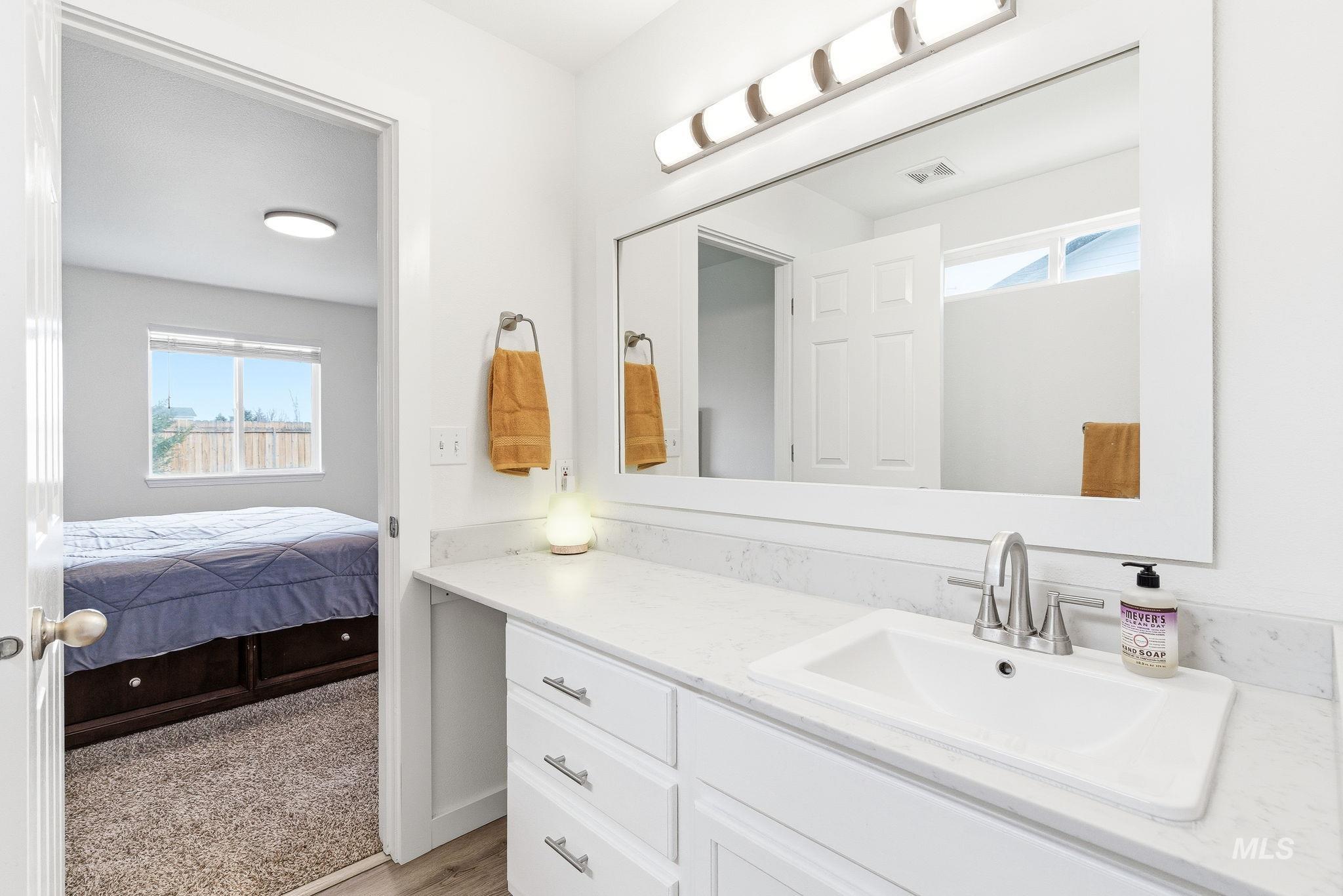 696 West Rams Hill Street Kuna, ID 83634 - Photo 30 of 46 Ensuite bathroom featuring healthy amount of natural light, vanity, light wood-type flooring, and light colored carpet