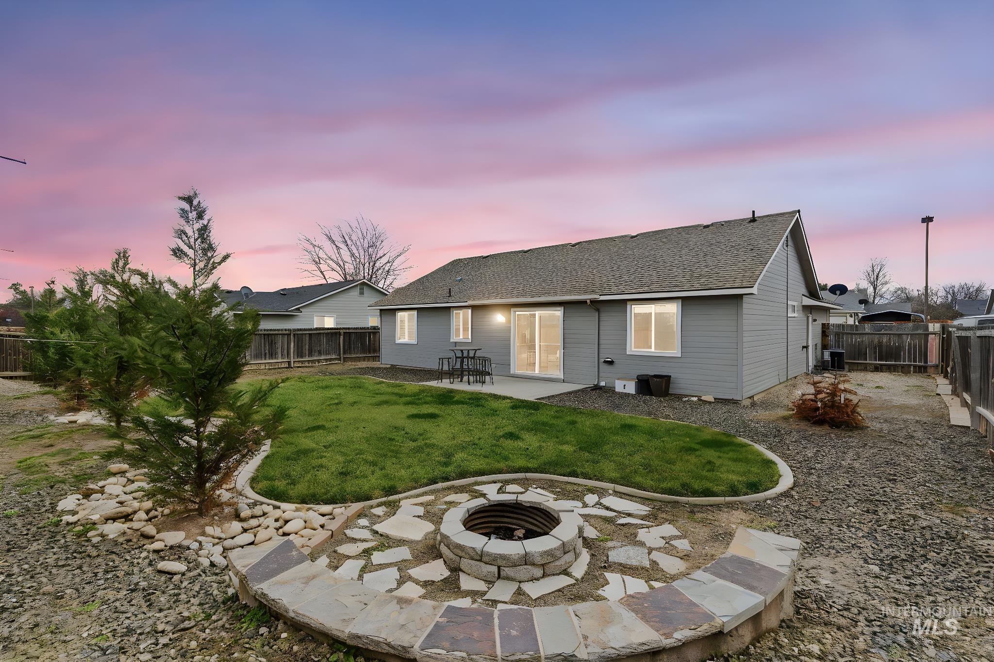 696 West Rams Hill Street Kuna, ID 83634 - Photo 43 of 46 Rear view of property featuring a patio, a fenced backyard, a shingled roof, and an outdoor fire pit