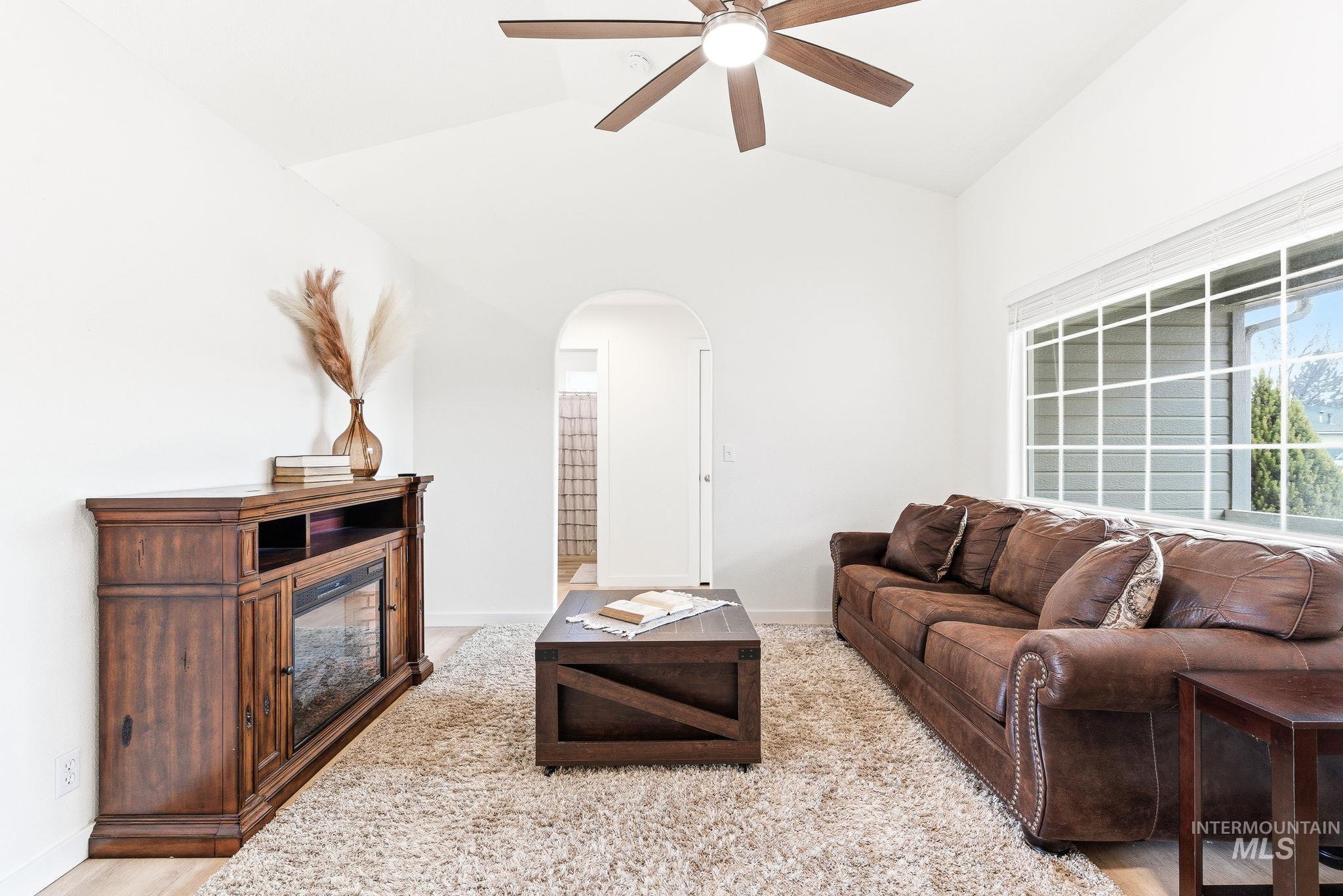 696 West Rams Hill Street Kuna, ID 83634 - Photo 6 of 46 Living area featuring arched walkways, a ceiling fan, vaulted ceiling, and light wood-style flooring