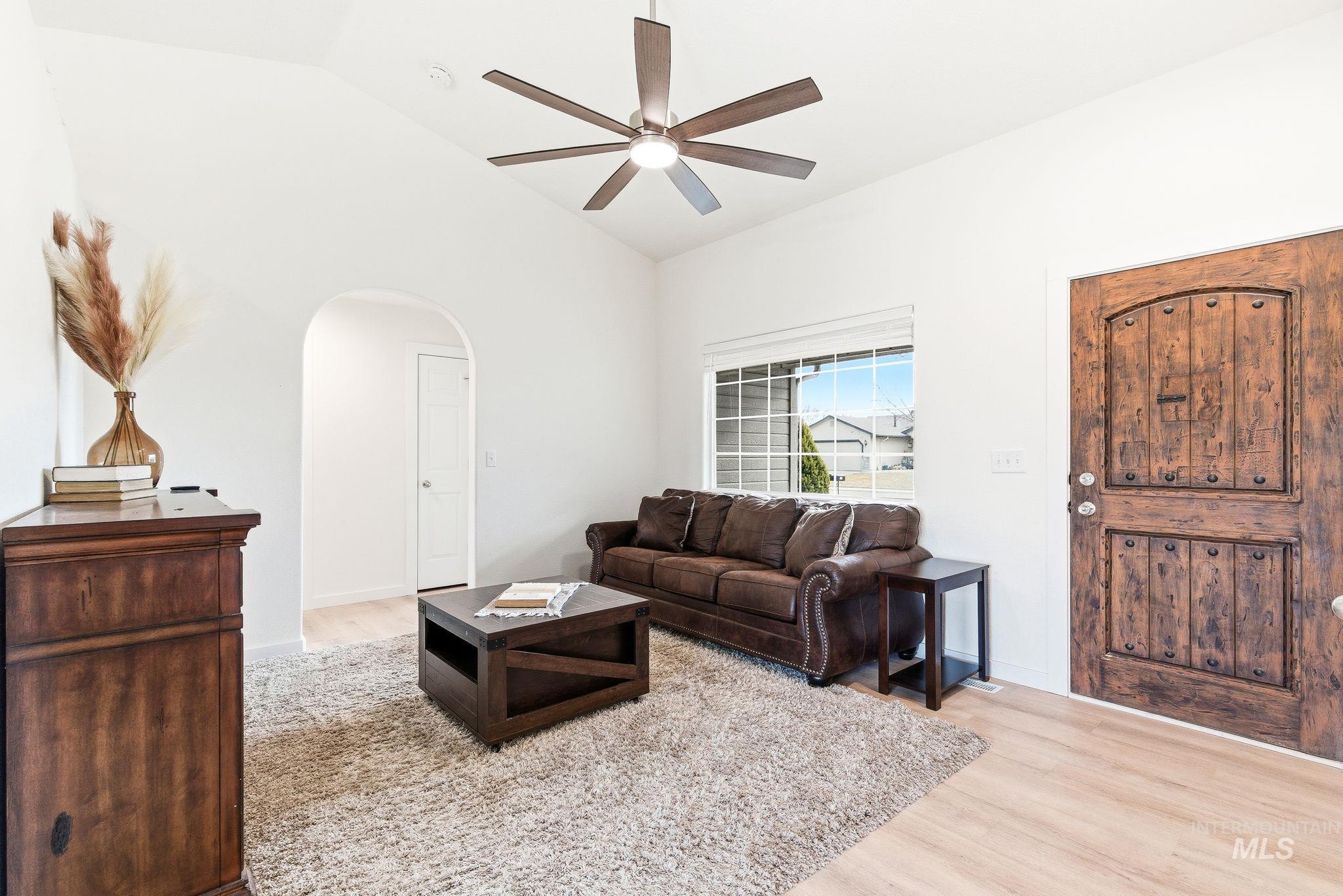 696 West Rams Hill Street Kuna, ID 83634 - Photo 7 of 46 Living area featuring arched walkways, light wood-type flooring, ceiling fan, and lofted ceiling
