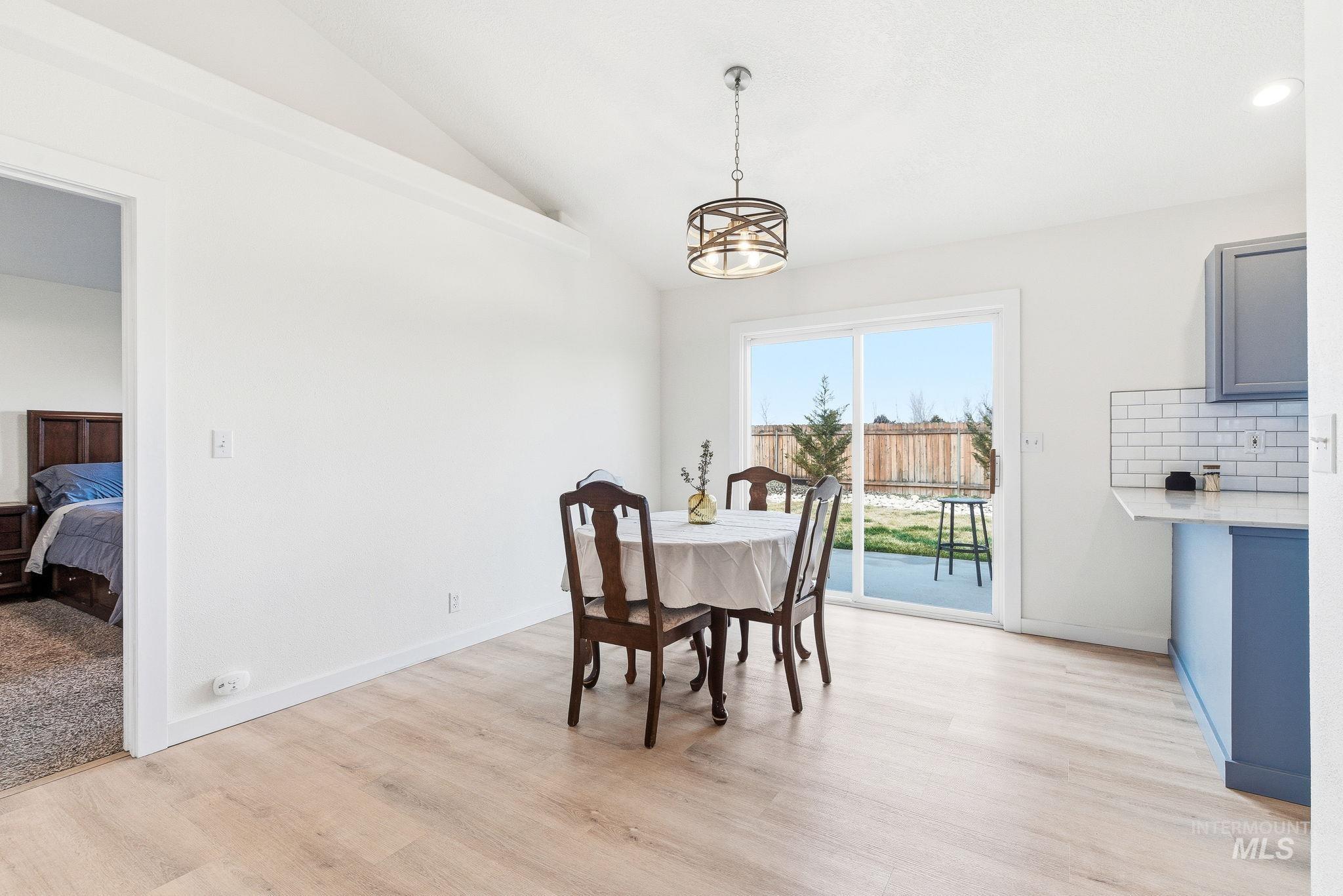 696 West Rams Hill Street Kuna, ID 83634 - Photo 10 of 46 Dining space with lofted ceiling, light wood-style flooring, and a chandelier