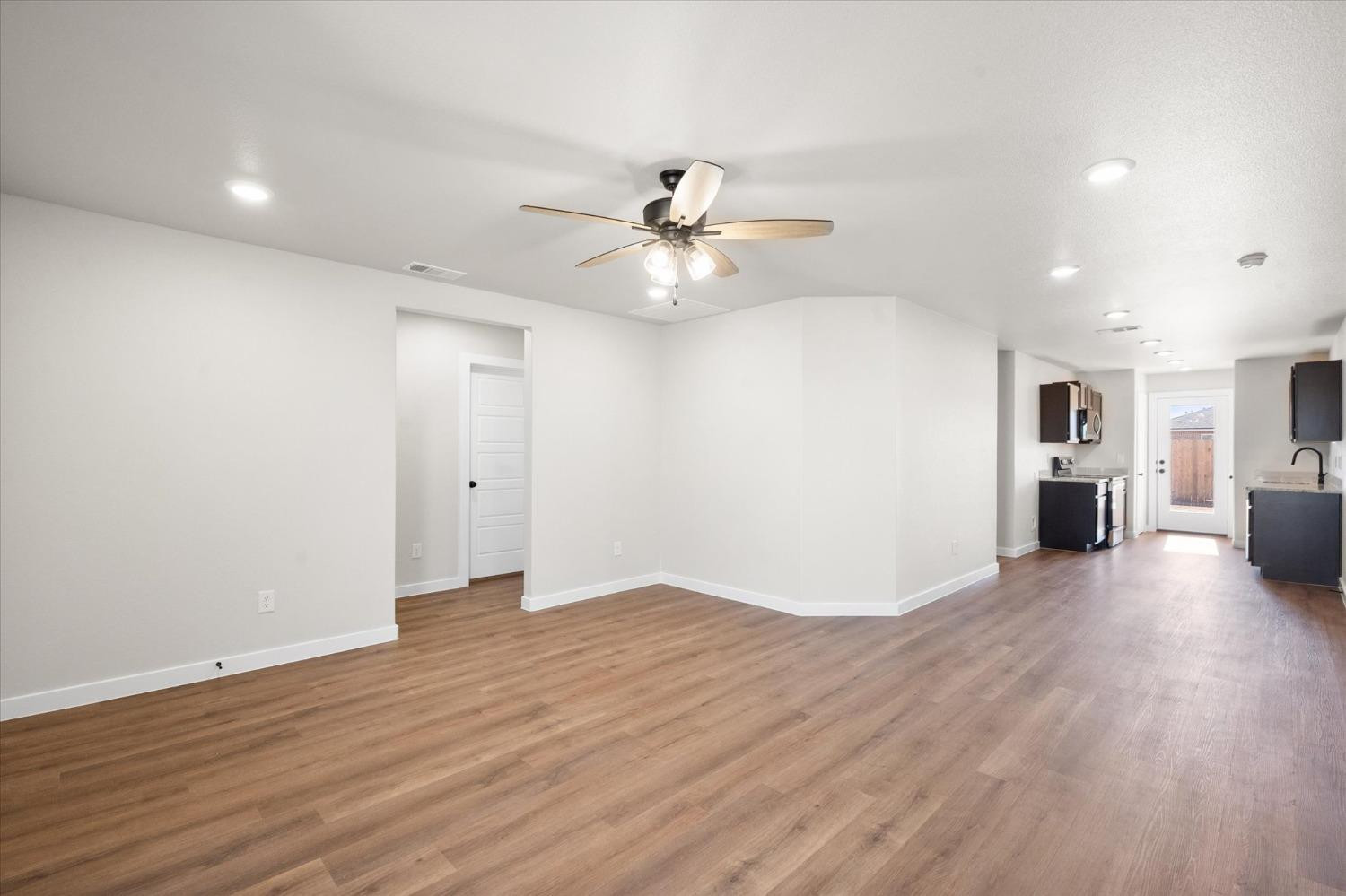 5519 Queens Street Lubbock, TX 79416 - Photo 5 of 21 a view of a livingroom with a kitchen island wooden floor and a ceiling fan