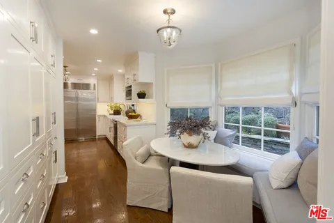 a kitchen with stainless steel appliances kitchen island granite countertop a refrigerator a sink a dining table and chairs