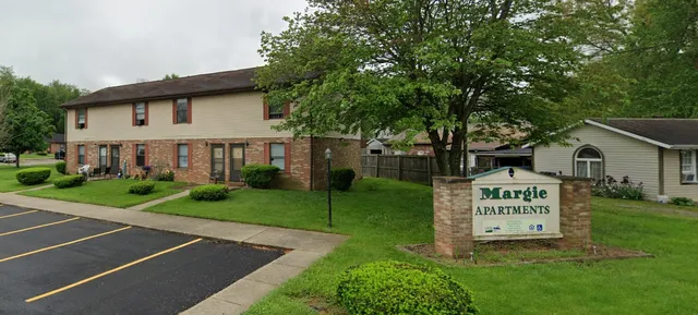 a view of a park that has a sign board large trees
