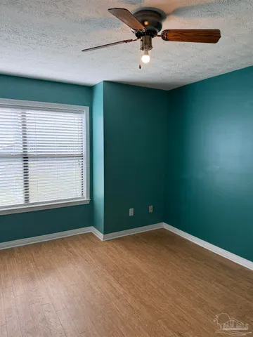 an empty room with windows and fan