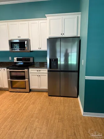 a kitchen with granite countertop a sink a stove top oven and cabinetry