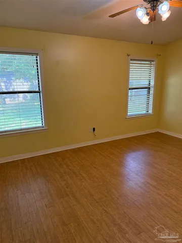 a view of an empty room with wooden floor and a window