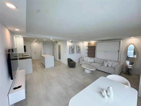a living room with furniture a white wall space and a large window