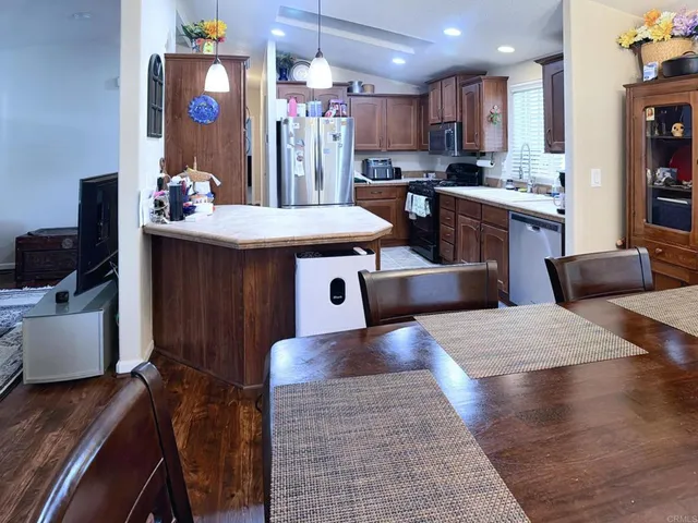 a kitchen with stainless steel appliances kitchen island granite countertop a sink dishwasher stove and white cabinets