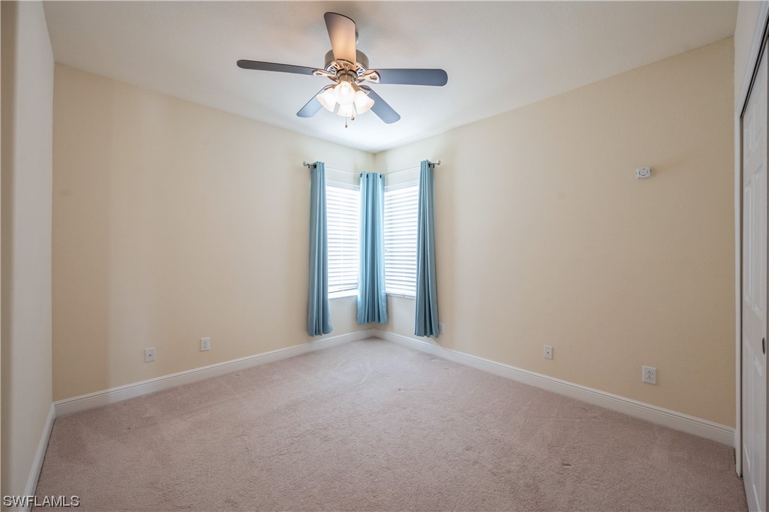19658 Tesoro Way Estero, FL 33967 - Photo 19 of 25 an empty room with a chandelier fan and windows