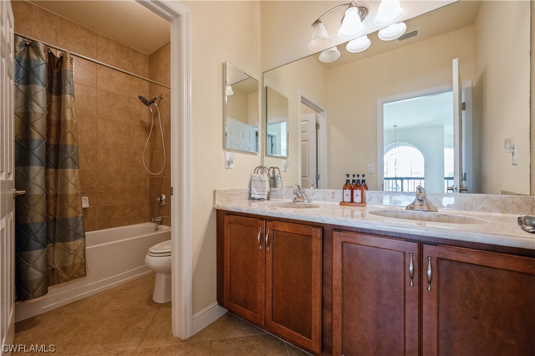 19658 Tesoro Way Estero, FL 33967 - Photo 22 of 25 a bathroom with a double vanity sink toilet mirror and shower