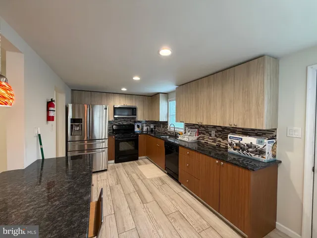a kitchen with stainless steel appliances kitchen island granite countertop a stove top oven and sink