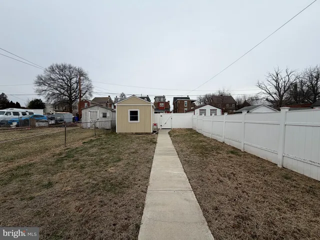 a view of a white house next to a yard with wooden fence