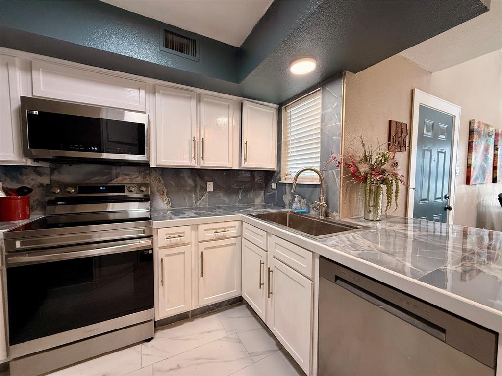 9807 Walnut Street, Unit D205 Dallas, TX 75243 - Photo 11 of 20 a kitchen with sink a microwave a stove and cabinets