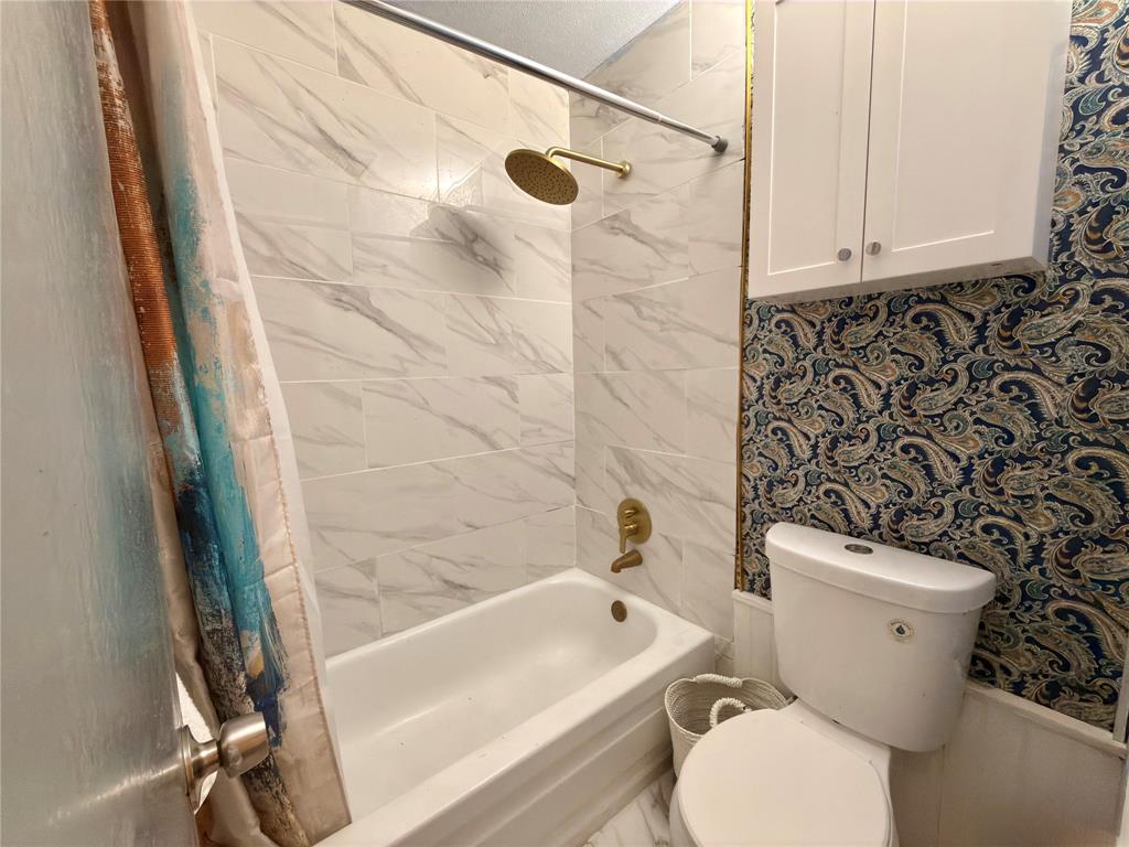 9807 Walnut Street, Unit D205 Dallas, TX 75243 - Photo 16 of 20 a white toilet sitting next to a bath tub and a shower