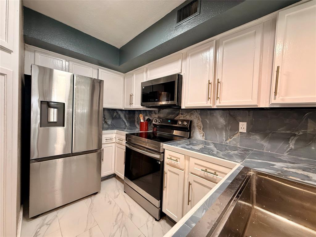 9807 Walnut Street, Unit D205 Dallas, TX 75243 - Photo 10 of 20 a kitchen with stainless steel appliances granite countertop a refrigerator sink and cabinets
