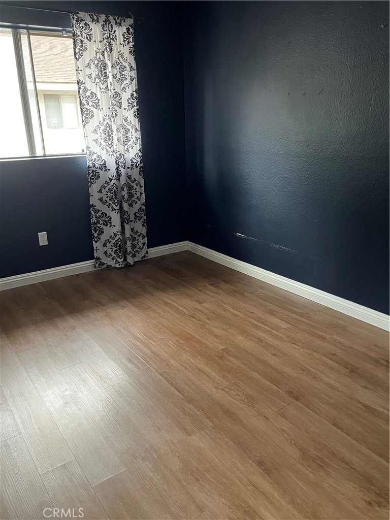 3073 Gladstone Street, Unit 4 Pomona, CA 91767 - Photo 4 of 10 an empty room with wooden floor and windows